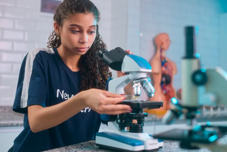 Estudante utilizando microscópio no laboratório de ciências